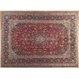 A KESHAN CARPET,PERSIA,MODERN the red field with a dark blue and ivory floral medallion, similar