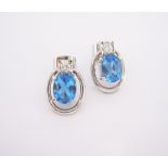 A PAIR OF BLUE TOPAZ AND DIAMOND EARRINGS each centred with an oval-shaped mixed-cut blue topaz