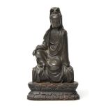 A CHINESE PATINATED BRONZE FIGURE OF GUANYIN modelled seated with right knee raised, dressed in long