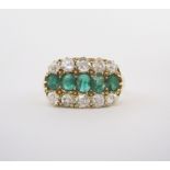 AN EMERALD AND DIAMOND RING designed as a row of five oval mixed-cut emeralds between borders of