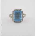 A BLUE TOPAZ AND DIAMOND RING claw set with an emerald-cut blue topaz weighing approximately 2.