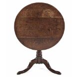 A GEORGE III STYLE TEAK TILT-TOP TABLE the oval top above a turned support, on three outswept legs