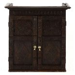 A GEORGE III OAK WALL HANGING SPICE CUPBOARD the outset pediment above a carved frieze, a pair of