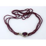 A RHODOLITE GARNET AND DIAMOND CHOCKER comprised of three strands of garnet beads, the clasp centred