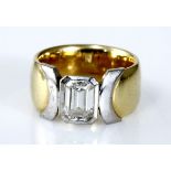 A DIAMOND RING the broad band centred with a bezel-set emerald-cut diamond weighing approximately