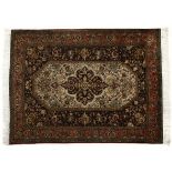 A QUM SILK RUG the ivory field with a floral dark blue medallion with similar spandrels all with