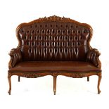 A VICTORIAN STYLE LEATHER UPHOLSTERED SETTEE the foliate-carved top rail above a button-back, padded