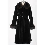 A BLACK VELVET COAT WITH FOX FUR COLLAR AND CUFFS. Button down coat with tie belt and patch pockets.