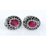 A PAIR OF RUBY AND BLACK DIAMOND EARRINGS each centred with an oval mixed-cut ruby weighing