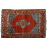 AN AFGHAN RUG, MODERN the plain red field with a stylise steppe skyblue medallion and spandrells