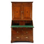 AN OAK AND INLAID SECRÉTAIRE CABINET, EARLY 19TH CENTURY in two parts, the outswept cornice above