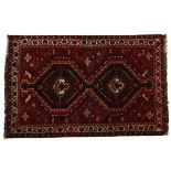 A SHIRAZ RUG, PERSIA, MODERN the red field with two blue diamond medallions within an ivory flower