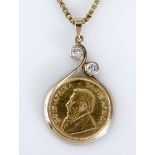 A COIN PENDANT set with a 1/4oz Kruger Rand coin, within a metal surround, bezel-set with two