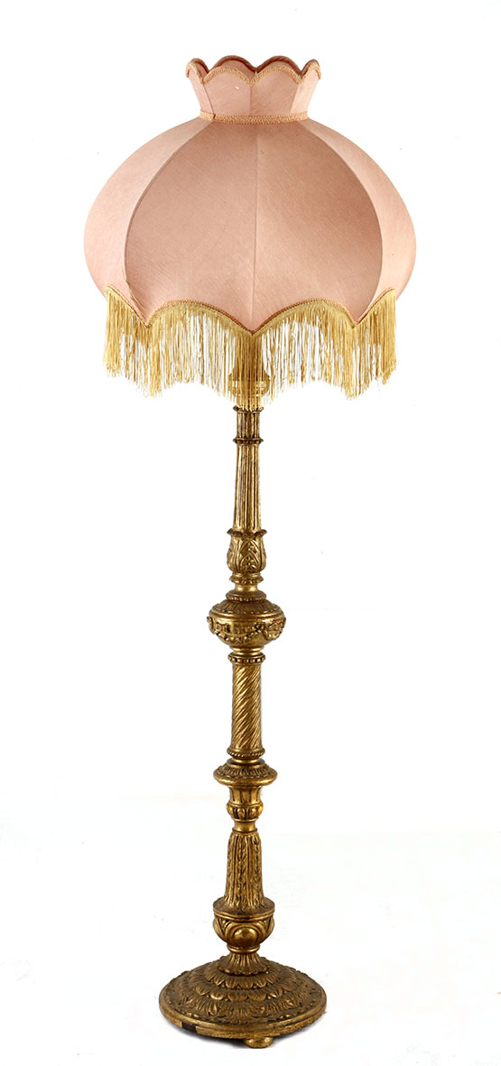 A VICTORIAN STYLE GILTWOOD LAMP the bell-shaped fringed shade on a leaf-carved fluted column, on a