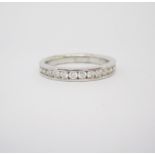 A DIAMOND HALF-ETERNITY RING channel set to the centre with a row of brilliant-cut diamonds weighing