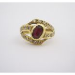 A RUBY AND DIAMOND RING of cross-over design, centred with an oval ruby measuring approximately 0.