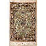 A QUM SILK RUG, PERSIA, MODERN the pale turquoise field with a small black floral medallion, similar