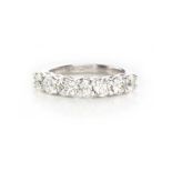 A DIAMOND HALF-ETERNITY RING claw set to the centre with a row of brilliant-cut diamonds weighing