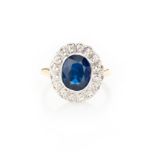 A SAPPHIRE AND DIAMOND RING of flower-head design, collet set to the centre with an oval mixed-cut