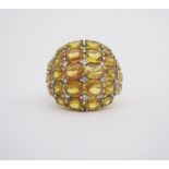 A YELLOW SAPPHIRE AND DIAMOND RING of bombe design, claw set to the centre with rows of oval mixed-
