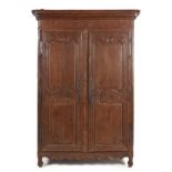 A FRENCH PROVENÇAL LOUIS XV STYLE OAK ARMOIRE the outswept pediment above a carved frieze