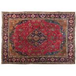 A TABRIZ CARPET, PERSIA, MODERN the red field with a geometric dark blue floral medallion, brown