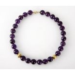 AN AMETHYST NECKLACE composed of amethyst beads, approximately 14,5mm in diameter, with fluted