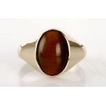 A TIGERS EYE RING centred with a bezel-set oval cabochon tigers eye, impressed 9ct, size U