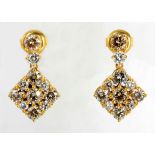 A PAIR OF DIAMOND EARRINGS each surmount claw-set with a champagne and white brilliant-cut