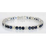 A SAPPHIRE AND DIAMOND BRACELET claw-set with thirty circular-cut sapphires weighing approximately