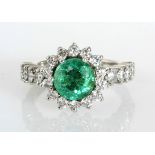AN EMERALD AND DIAMOND RING centered with a circular emerald weighing approximately 1.51cts, the