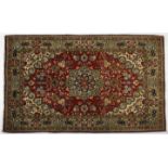 A QUM PART SILK RUG, PERSIA, MODERN the red field with a floral green and blue star medallion, ivory