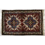 AN AFGHAN RUG, MODERN the red field with two sunburst medallions depicted in blue, ivory and