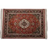 A QUM SILK RUG, PERSIA, MODERN the red field with a ivory floral medallion, black spandrels all with
