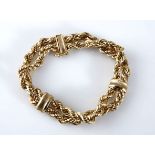 A GOLD BRACELET designed as two strands of a combination twisted rope, joined together by two