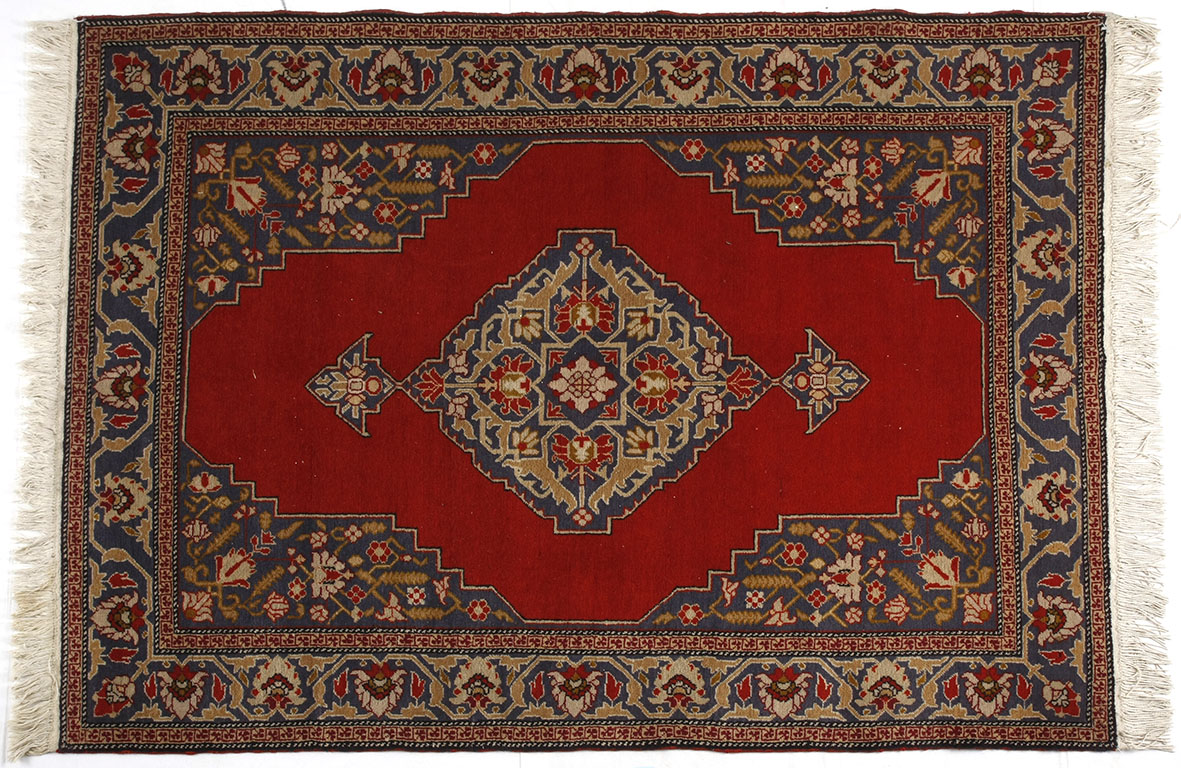 A TURKISH RUG, MODERN the madder field with two diamond medallions depicted in slate blue within a