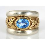 A BLUE TOPAZ RING the broad tapered band centred with a bezel-set oval mixed-cut blue topaz weighing