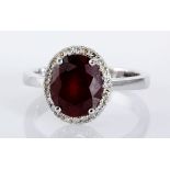 A RUBY AND DIAMOND RING centred with an oval mixed-cut fracture filled ruby weighing approximately