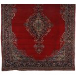 A KESHAN CARPET, PERSIA, MODERN the plain red field with a poly-chrome floral blue and beige