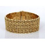 AN 18CT GOLD BRACELET the broad band composed of interlocking textured U-shaped links, with push