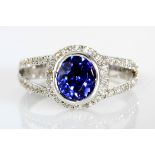 A TANZANITE AND DIAMOND RING centered with a bezel-set oval mix-cut tanzanite weighing approximately