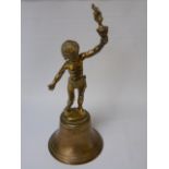 A bronzed bell with brass handle in the form of a boy holding a torch