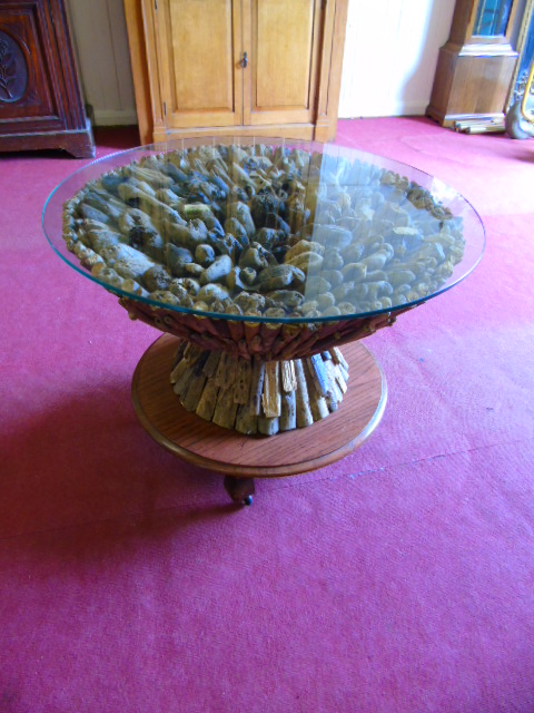 Circular driftwood coffee table glass top and raised on a wheeled wooden base