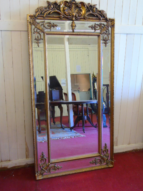 Large gilt framed mirror with floral top. Approx 72" high