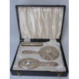 A cased 4 piece silver dressing table set with repousse decoration date marked Birmingham 1897