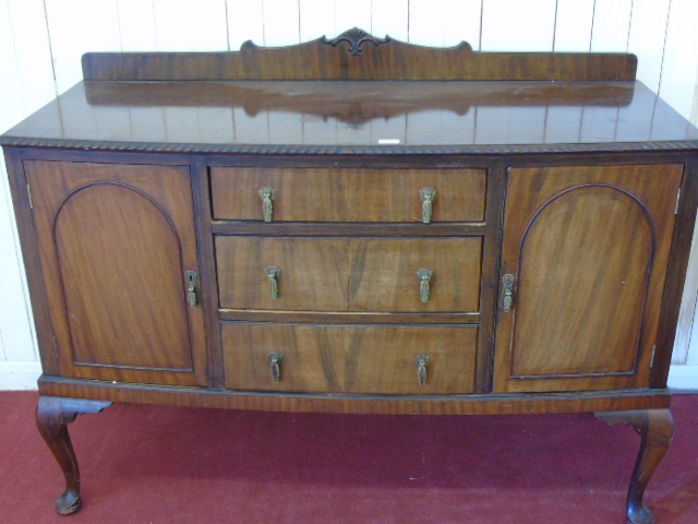 A mahogany sideboard fitted three drawers with cupboard doors to either side.