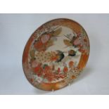 An oriental dish decorated with flowers and a peacock to the centre  Approx 12" diameter