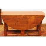 20th century heavy oak drop-leaf table raised on turned supports united by an understretcher,