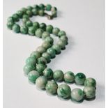 Single row necklet of fifty-one graduated jadeite beads, variegated green (uncertificated).