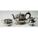 Silver three-piece tea set of baluster shape, the edge with scrolls at intervals, by Adie Brothers,